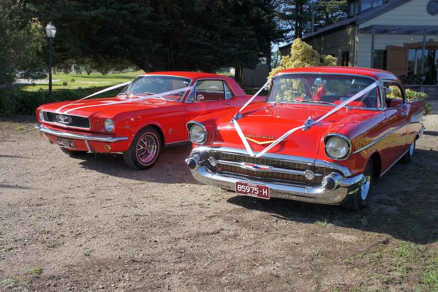 2 classic red cars at a wedding ceremony