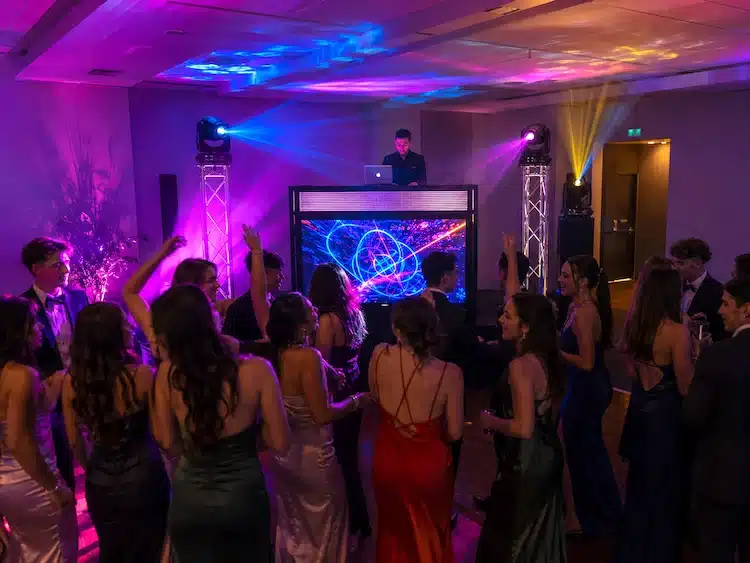 Armada Video DJ Booth entertaining guests at a school formal and valedictory celebration with students dancing in front of an elevated stage.